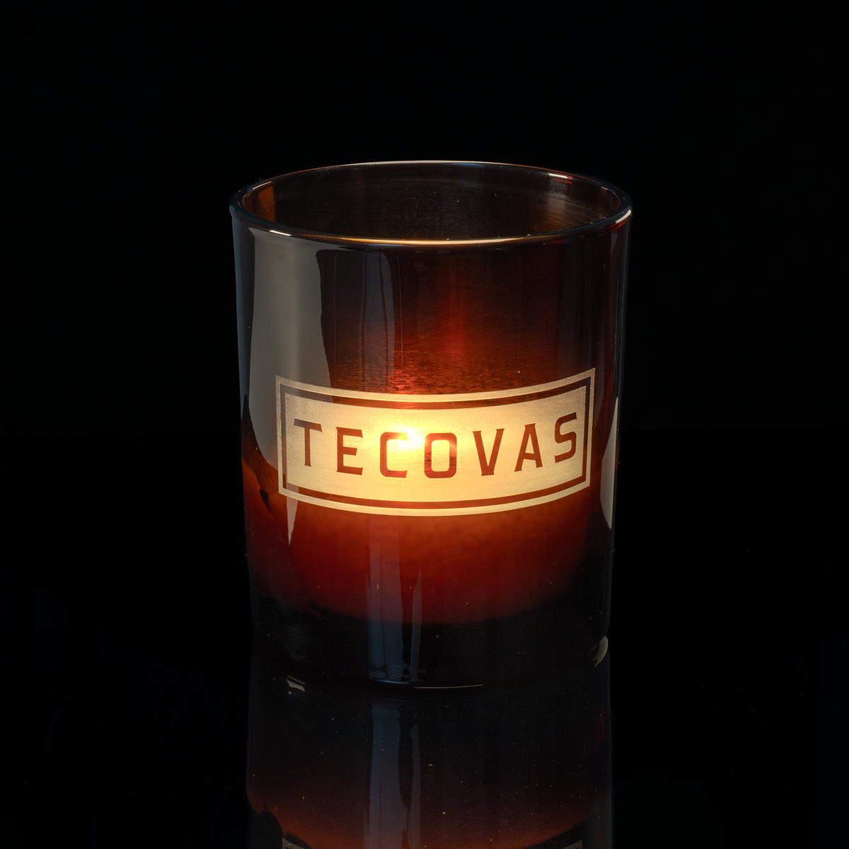 14 oz. Amber glass candle with custom engraved logo from Bath Promotions, shown lit — Lit version