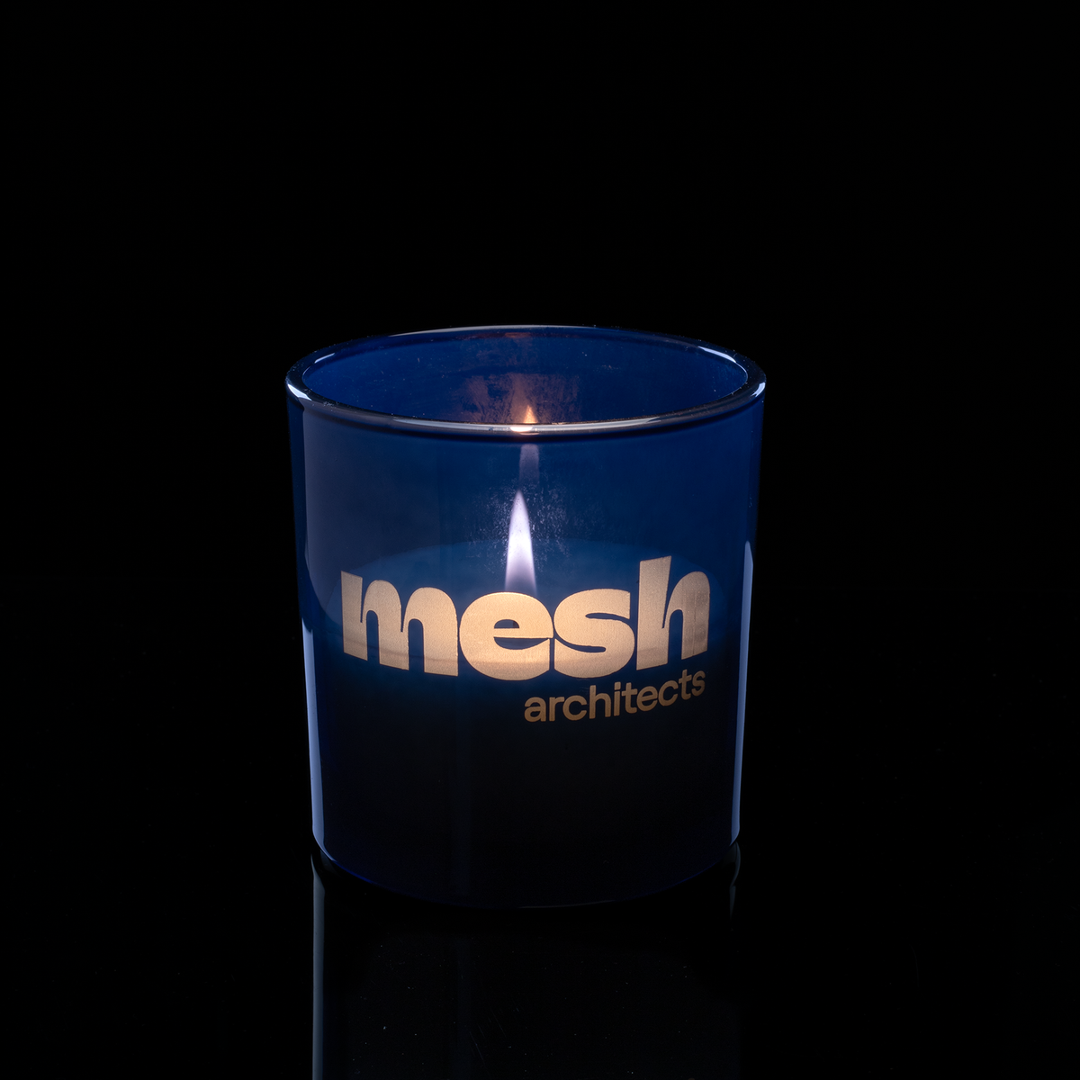 9 oz. Blue glass candle with custom engraved logo from Bath Promotions, shown lit — Lit version