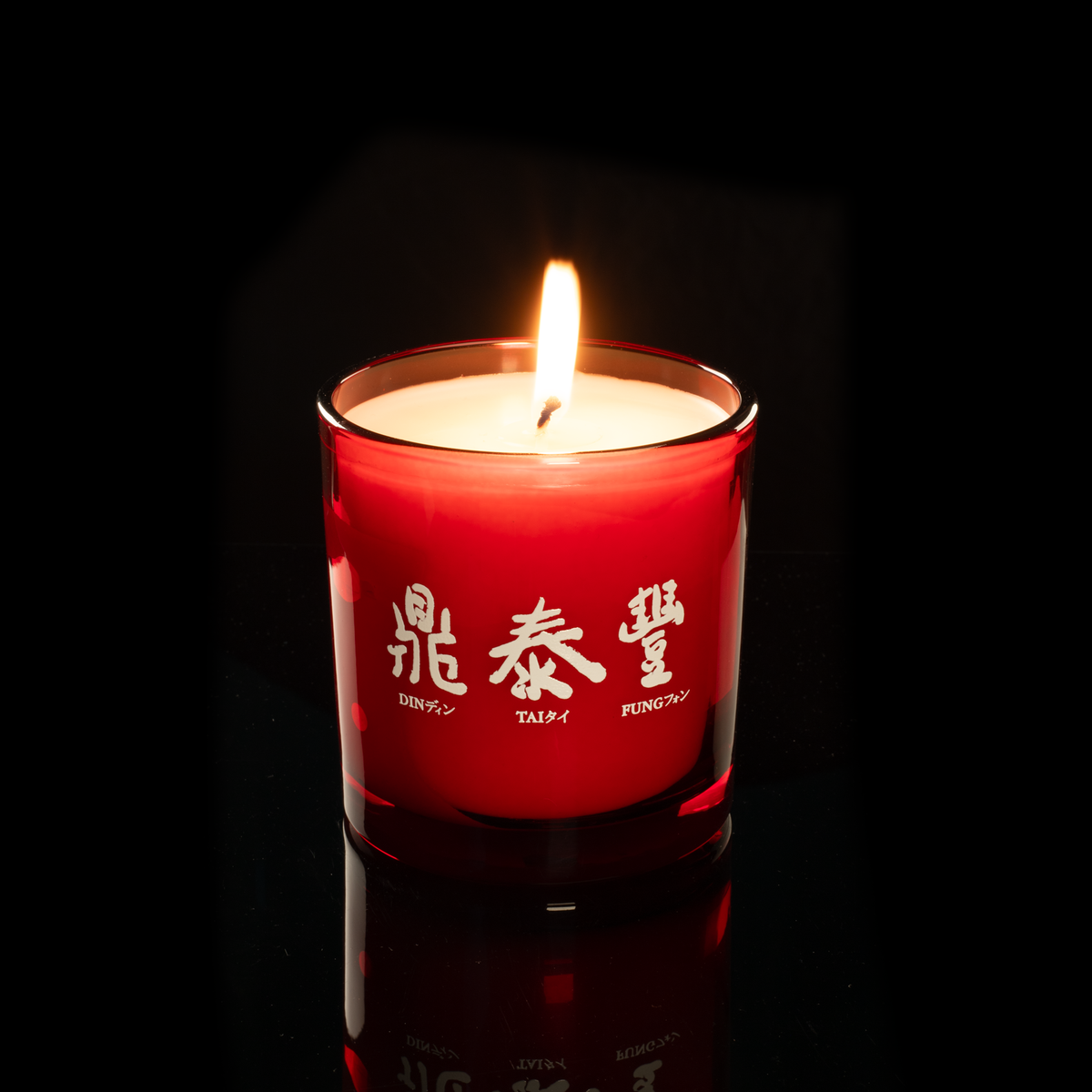 9 oz. Red glass candle with custom printed logo from Bath Promotions, shown lit — Lit version