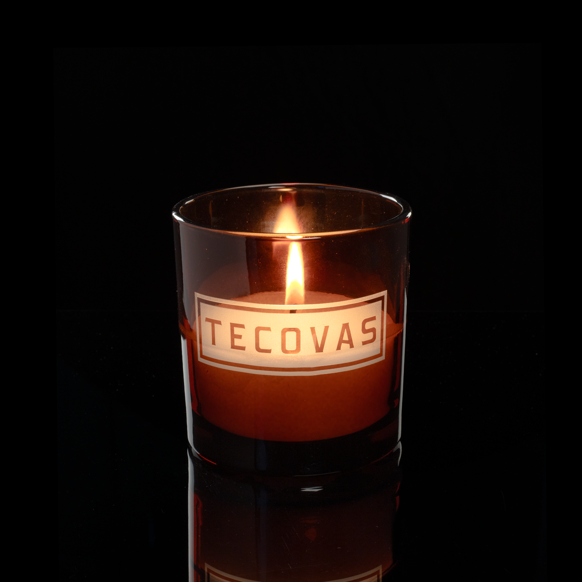 9 oz. Amber glass candle with custom engraved logo from Bath Promotions, shown lit — Lit version