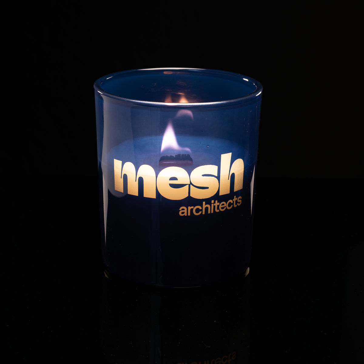14 oz. Blue glass candle with custom engraved logo from Bath Promotions, shown lit — Lit version