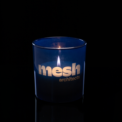 9 oz. Blue glass candle with custom engraved logo from Bath Promotions, shown lit — Lit version