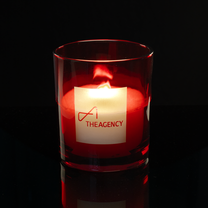 14 oz. Red glass candle with custom engraved logo from Bath Promotions, shown lit — Lit version