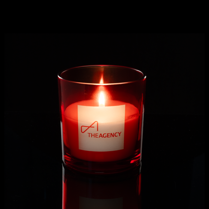 9 oz. Red glass candle with custom engraved logo from Bath Promotions, shown lit — Lit version