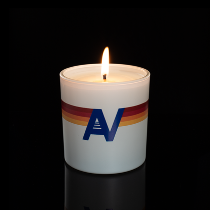 9 oz. White glass candle with custom printed logo from Bath Promotions, shown lit — Lit version