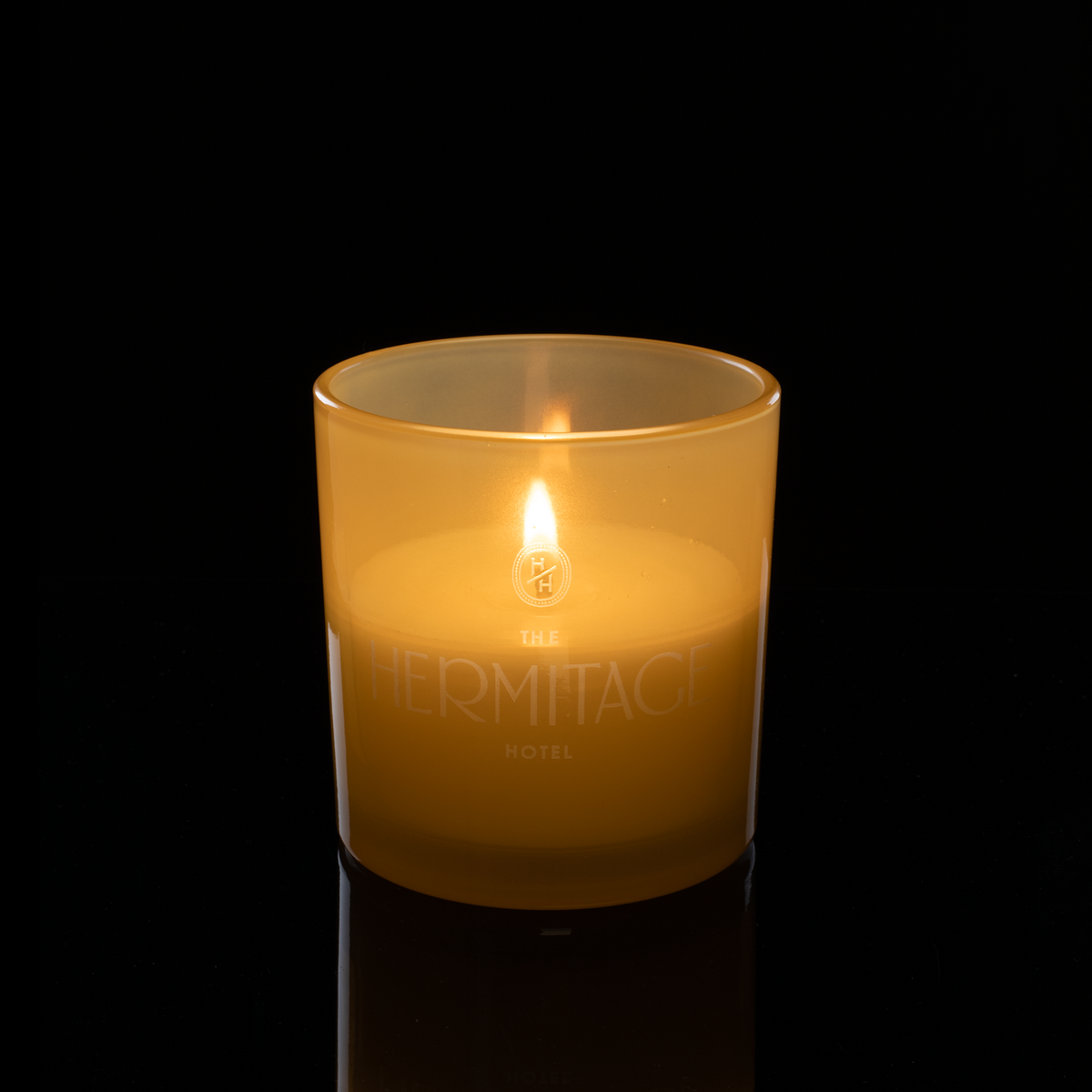 9 oz. Yellow glass candle with custom engraved logo from Bath Promotions, shown lit — Lit version