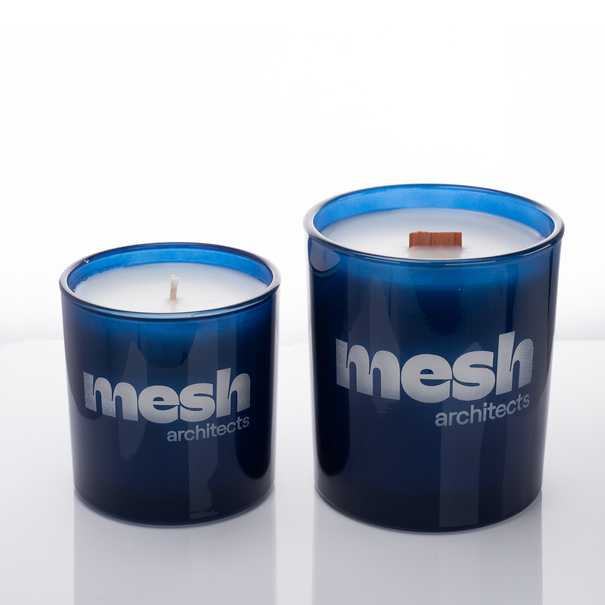 Blue glass candles, 9 oz. beside 14 oz., both laser engraved with the same logo, from Bath Promotions