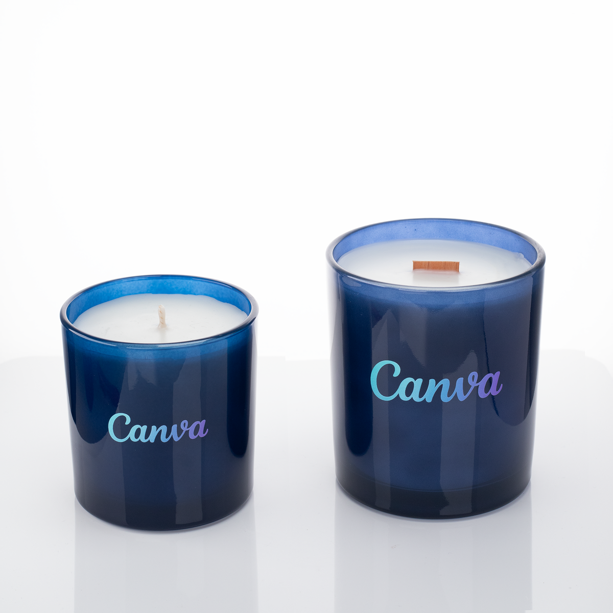Blue glass candles, 9 oz. beside 14 oz., both custom printed with the same logo, from Bath Promotions