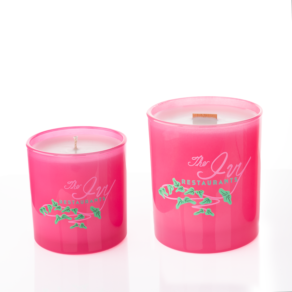 Pink glass candles, 9 oz. beside 14 oz., both custom printed with the same logo, from Bath Promotions