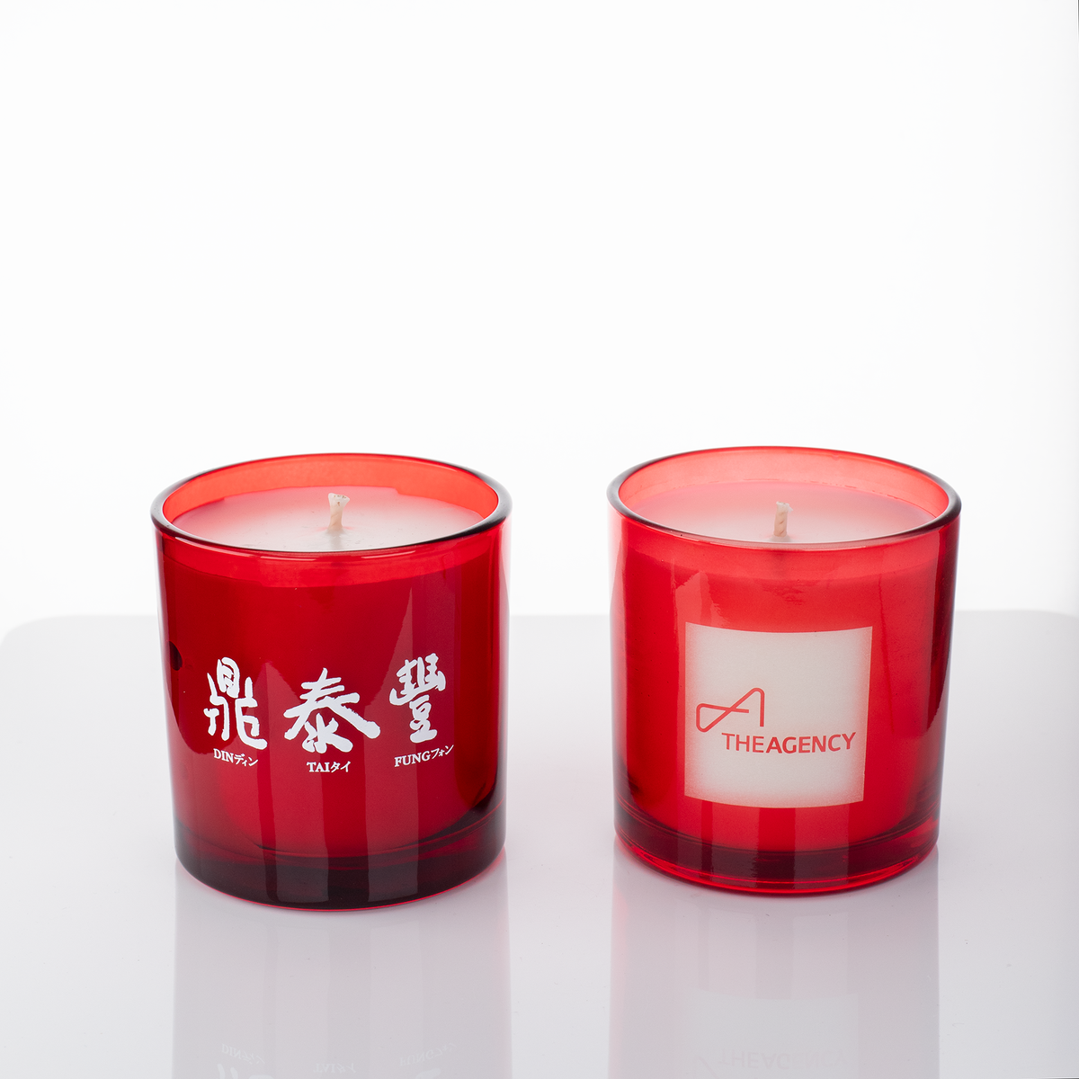 Red glass, two 9 oz. candles side by side, one custom printed and one laser engraved, from Bath Promotions