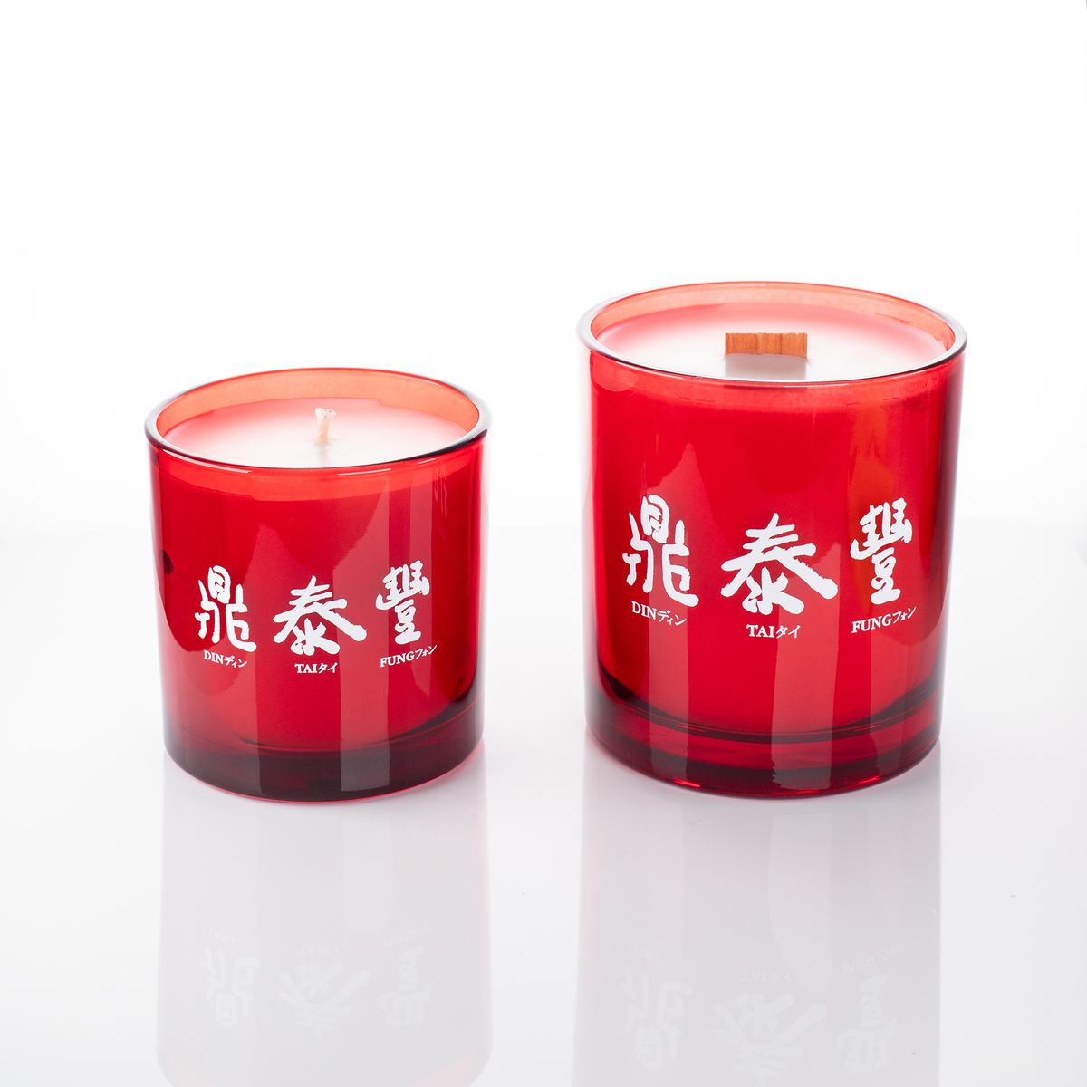 Red glass candles, 9 oz. beside 14 oz., both custom printed with the same logo, from Bath Promotions