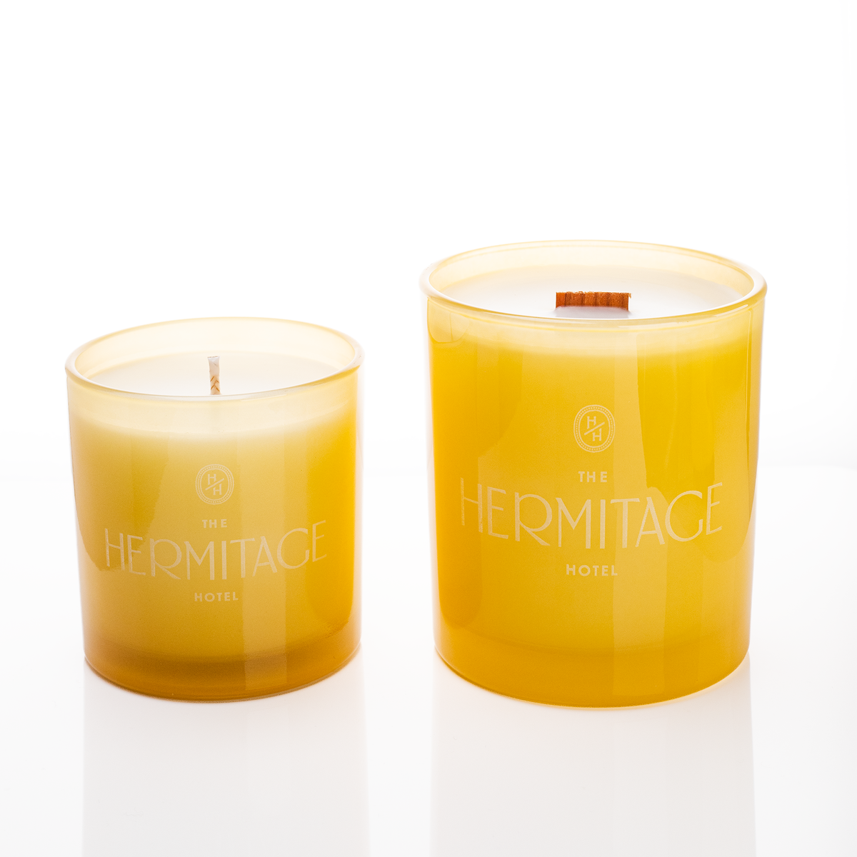 Yellow glass candles, 9 oz. beside 14 oz., both laser engraved with the same logo, from Bath Promotions