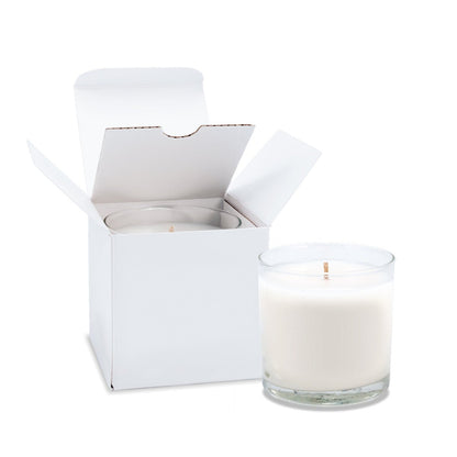 Two 6 oz clear glass candles with white wax and cotton wicks - one inside an open white gift box and one standing beside it.