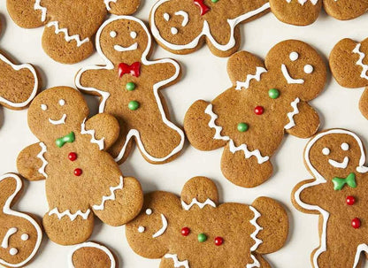 Brown gingerbread cookies decorated with white icing, red and green candy buttons, arranged on white surface.