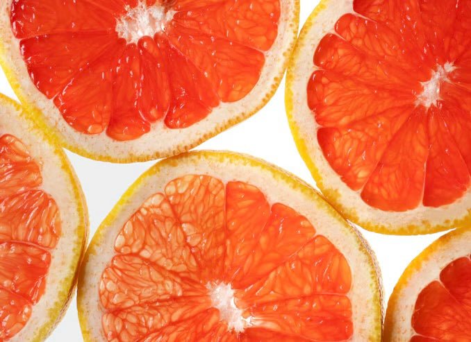 Sliced blood oranges showing bright red-orange segmented flesh with white centers and yellow-orange rinds.