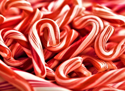 Multiple red and white striped candy canes with curved hooks scattered and overlapping in dense arrangement.